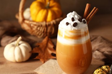 Bir bardak portakal kabaklı latte, ahşap masada, yakın plan.