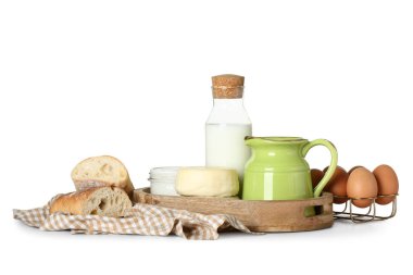 Farklı süt ürünleri, ekmek, yumurta ve peçete içeren ahşap tepsi.