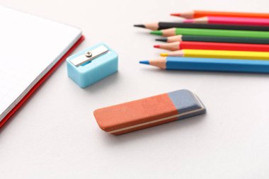 Keskinleştirici, defter ve beyaz arkaplanda renkli kalemler ile silgi