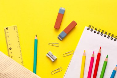 Sarı arkaplanda farklı kırtasiye malzemesi olan silgi