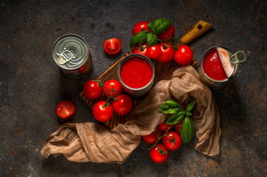 Koyu arkaplanda fesleğen yapraklı ve sebzeli teneke kutu domates ezmesi.
