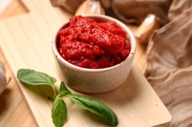 Bir kase lezzetli domates ezmesi, peçeteye fesleğen yaprağı, yakın plan.