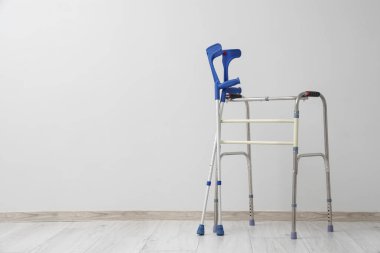 Koltuk değnekleriyle odada yürüyen bir doktor.