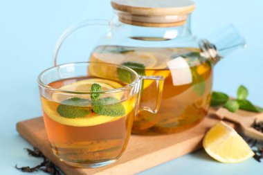 Çaydanlık ve bir fincan lezzetli meyve çayı mavi arka planda, yakın plan.