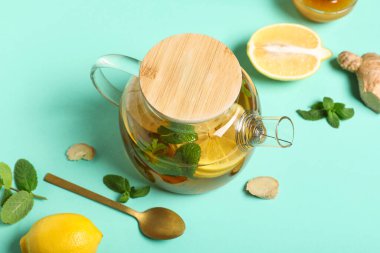 Cam çaydanlık dolusu lezzetli meyve çayı ve turkuaz arka plandaki malzemeler, yakın plan.