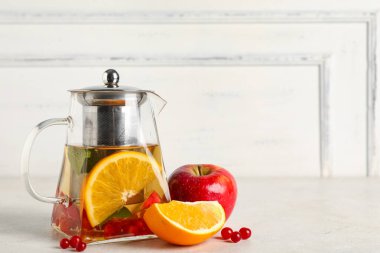 Lezzetli meyve çaydanlığı ve beyaz grunge masasında malzemeler, yakın plan.