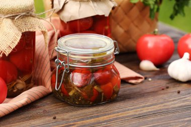 Dışarıdaki ahşap masada sarımsaklı kavanozlar dolusu domates.