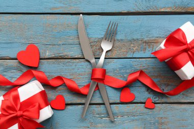 Sevgililer Günü için sofra takımı, dekoratif kalpler, kurdele ve tahta arka planda hediye kutuları.