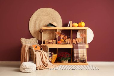 Hasır koltuklu, raf üniteli ve sonbahar yapraklı rahat bir oda.