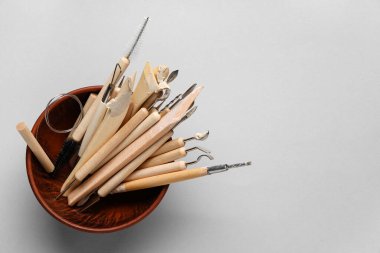 Gri arkaplanda bir takım heykeltraş araçları olan bir kase