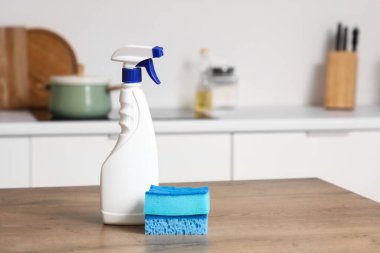 Mutfaktaki masada deterjan şişesiyle sünger temizliyorum.