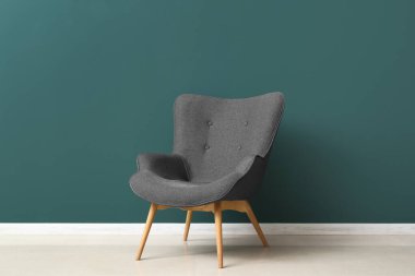 Modern grey armchair near green wall