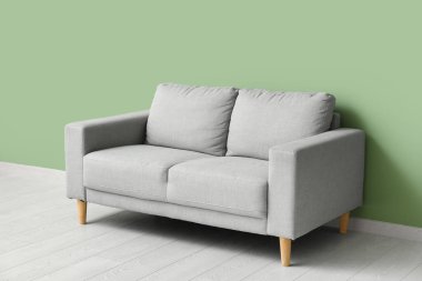 Yeşil duvarın yanındaki rahat gri kanepe