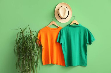 Yeşil arka planda asılı şık tişörtler ve şapkalar