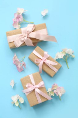 Şirin hediye kutuları ve cyan arka planda çiçekleri olan kompozisyon