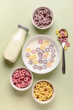 Yeşil arka planda sütü olan renkli mısır gevreği halkaları.