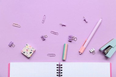 Leylak arka planında kırtasiye malzemesi olan defteri aç. Üst görünüm