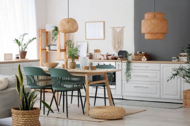 Masa, sandalye ve hasır pouf yemek odasının içinde tezgahın yanında.