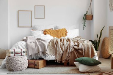 Yatak odasının içinde bavulla büyük, rahat bir yatak ve puf.