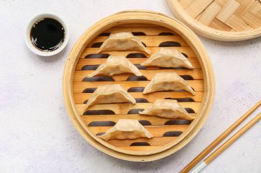 Lezzetli Japon gyoza 'lı bambu buharı ve beyaz arka planda bir kase soya sosu.
