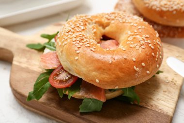 Tahta tahtada somon balığı ve roka arkaplanlı lezzetli simit sandviçi, yakın plan.