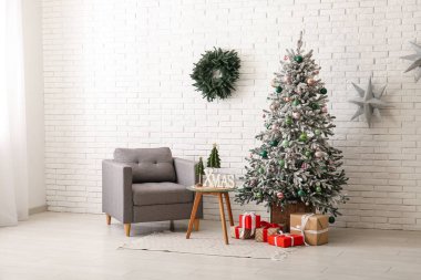 Oturma odasının içinde Noel çelengi, koltuk ve köknar ağacı var.