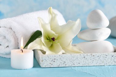 Yanan mum, spa taşları, havlu ve güzel zambak çiçekli kompozisyon.