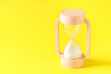 Sarı arka planda kum saati. Zaman yönetimi kavramı