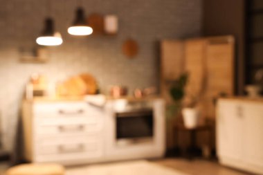 Tezgahlı bulanık mutfak manzarası, katlanan ekran ve akşamları parlayan lambalar