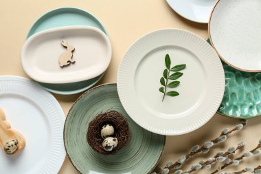 Different clean plates with quail eggs and pussy willow branches on light background. Easter celebration