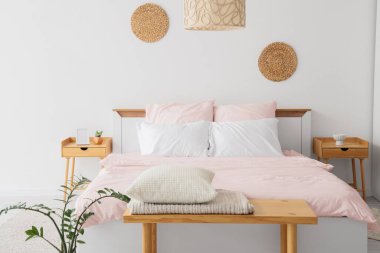 Şık pembe yataklı yatak, komodinli, banklı ve çiçekli yatak odası