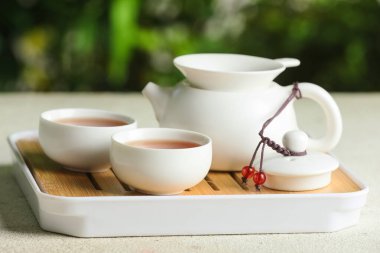 Çaydanlıklı tepsi ve beyaz grunge masasında seremoni için sıcak çay, yakın plan.