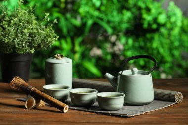 Çaydanlıklı bambu hasırı, bir fincan kibrit çayı ve ahşap masada seremoni için chasen, yakın plan.
