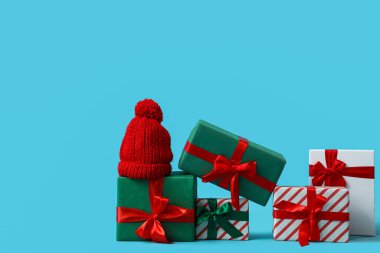 Noel hediyeleri ve mavi arka planda sıcak bir şapka