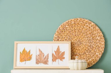 Yeşil duvarın yanında sonbahar yaprakları ve balkabağı olan çerçeve