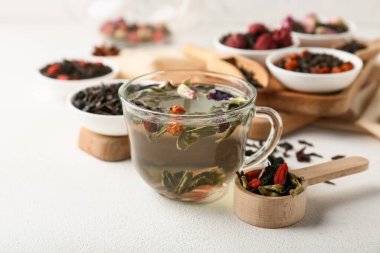 Bir fincan sıcak meyve çayı ve beyaz grunge arka planda kuru yapraklar, yakın plan.