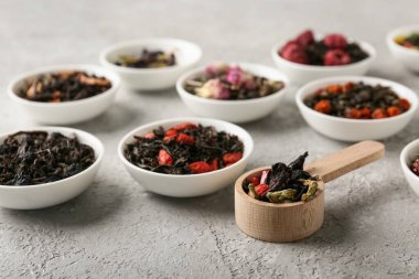 Gri grunge arka planında farklı kuru meyve çayları olan kaseler, yakın plan