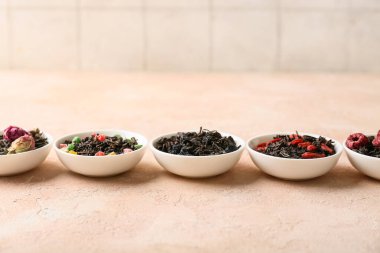 Pembe Grunge arka planında farklı kuru meyve çayları olan kaseler, yakın plan.