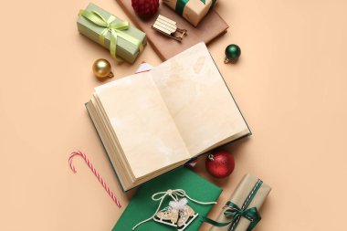 Noel topları, baston şekerler ve bej arka planda hediye kutuları olan boş bir kitap.
