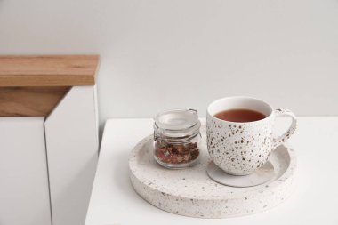 Yatak odasındaki masada çay ve kuru amber çiçeğiyle bardak altlığı.