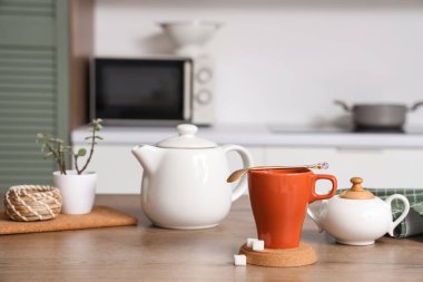 Mutfaktaki masada kaşık, bardak altlığı ve şekerli çay.