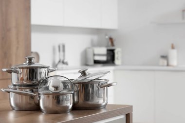 Mutfaktaki ahşap masada paslanmaz tencereler, yakın plan.