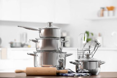 Mutfaktaki siyah masada paslanmaz tencere ve çatal bıçak.