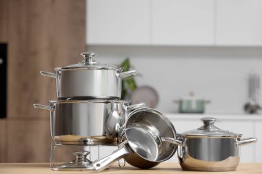 Mutfaktaki ahşap masada paslanmaz tencereler, yakın plan.