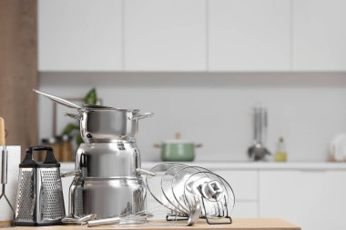 Mutfaktaki ahşap masada paslanmaz tencere ve çatal bıçak.