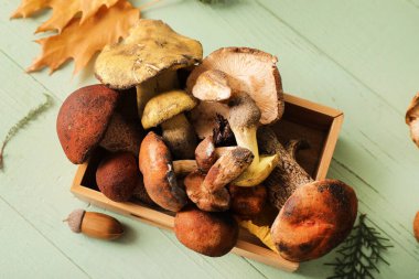 Yeşil ahşap arka planda taze mantarlı ahşap kutu, yakın plan.