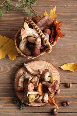 Hasır sepet ve ahşap arka planda taze mantarlarla dur.