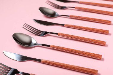 Pembe arka planda gümüş çatal bıçak sırası