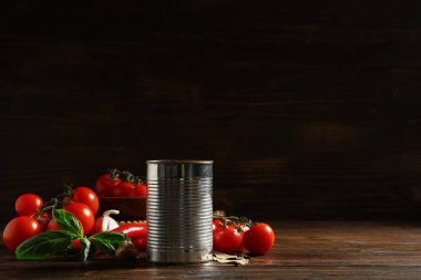 Teneke kutu lezzetli domates ezmesi ve ahşap arka planda farklı malzemeler.