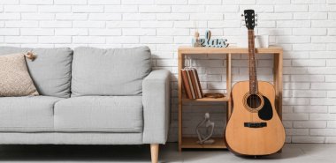 Modern gitar, raf ünitesi ve oturma odasında gri kanepe.